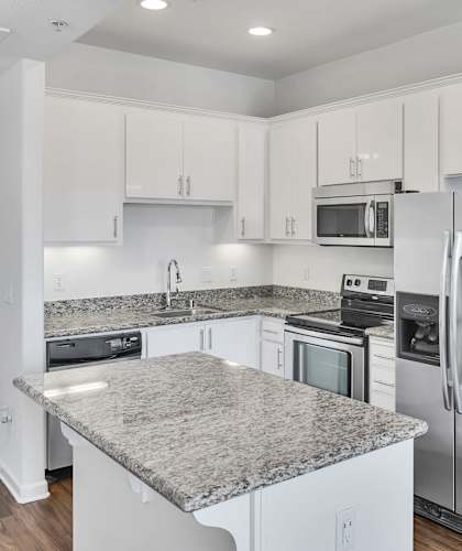 a kitchen with white cabinets and stainless steel appliances and granite counter tops at Aviara Apartments, San Jose, California