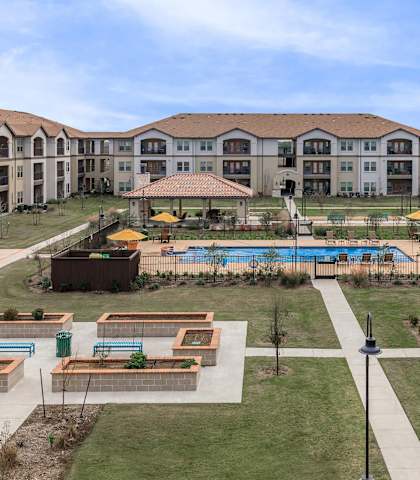an aerial view of an outdoor area with a pool and buildingsat Mariposa at Harris Road Arlington 55+ Apartments, Arlington, TX