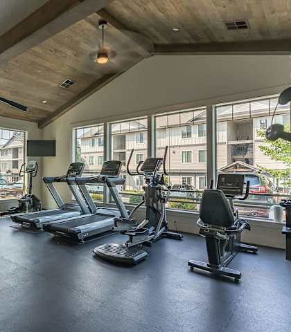A gym with a variety of equipment including treadmills, weights, and a stationary bike at Sandyplace Apartment Homes, Sandy, 97055
