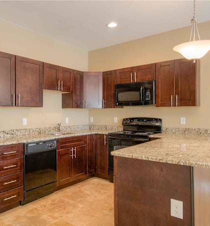 A kitchen with brown cabinets and a black refrigerator.