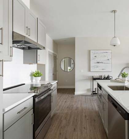 A modern kitchen with a white countertop and stainless steel appliances.