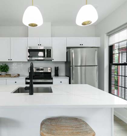 A modern kitchen with a white countertop and black appliances.