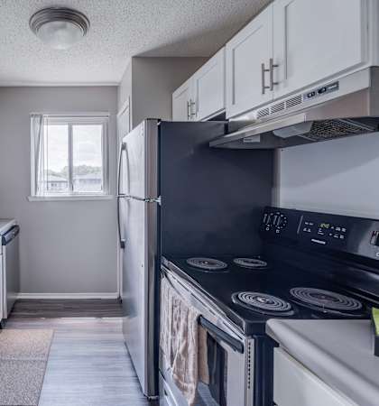 A kitchen with white cabinets and a black refrigerator.