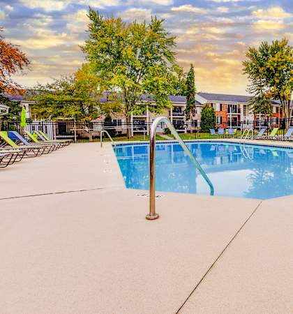 A swimming pool surrounded by trees and chairs.