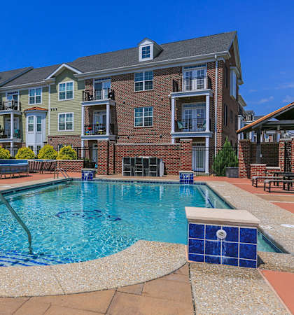 A swimming pool surrounded by a brick patio and a small brick building.