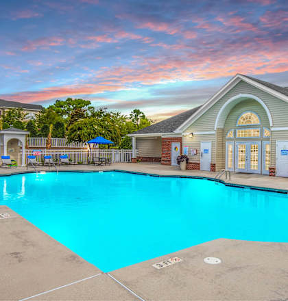 A swimming pool in front of a building with a sunset in the background.