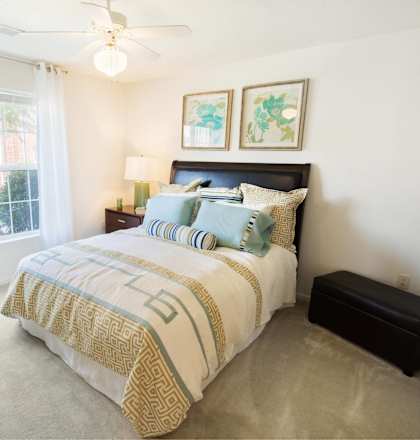 A bedroom with a bed, nightstand, and window.