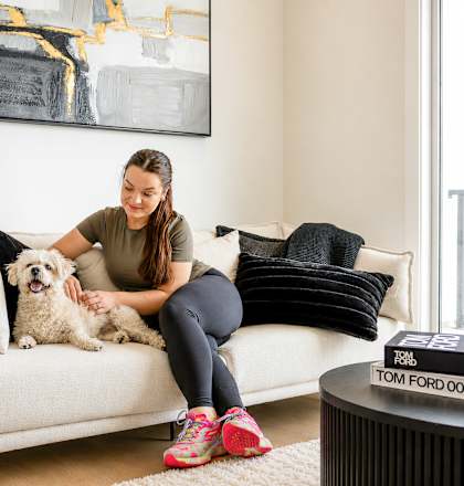 A woman is sitting on a couch with her dog.
