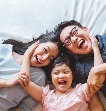 Family of three lying on bed at Normandy Woods in Riviera East, Houston, TX, 77015