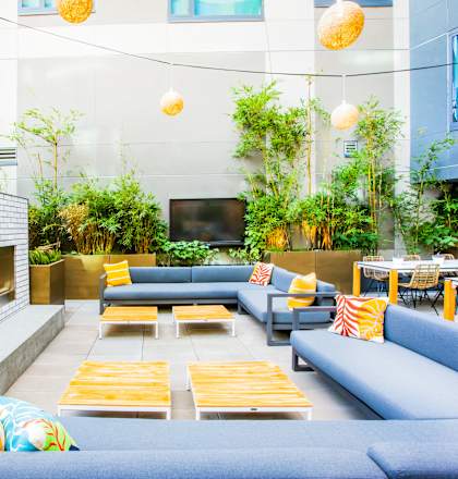 A modern outdoor seating area with blue couches and yellow cushions.at The Rise, California