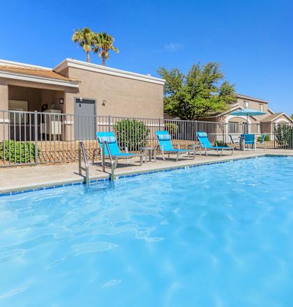 A swimming pool surrounded by chairs and a fence.