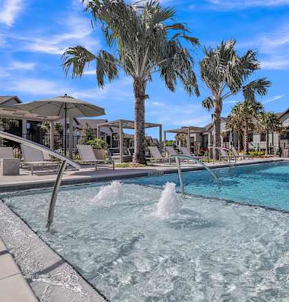 a swimming pool with palm trees and buildings in the background at Canter Ocala, FL 34474