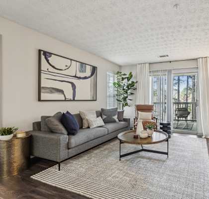 A living room with a grey couch, a coffee table, and a painting on the wall.