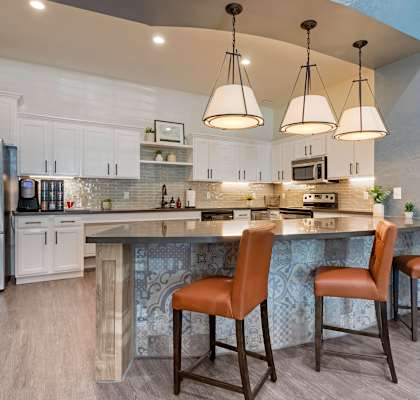 a kitchen with a large island with three chairs at Summerwind in Pearland 77584