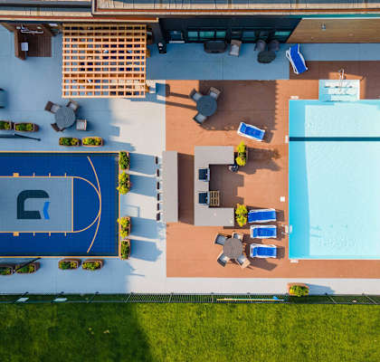 A large outdoor swimming pool with a basketball court and lounging area at G17 Apartments at Tamarack, Edmonton, AB