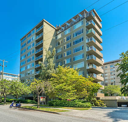 A modern apartment building with a parking lot in front.