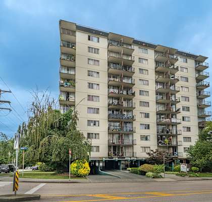 A large apartment building with balconies and a yellow crosswalk in front.