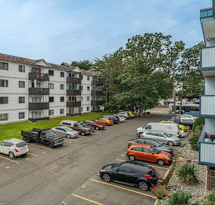 A parking lot with cars and apartment buildings in the background.