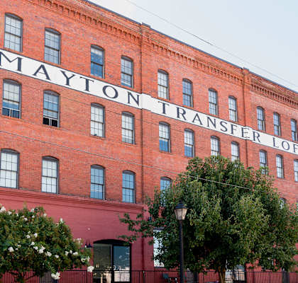 a large brick building with a sign on the side of it at Mayton Transfer Lofts, Virginia, 23803