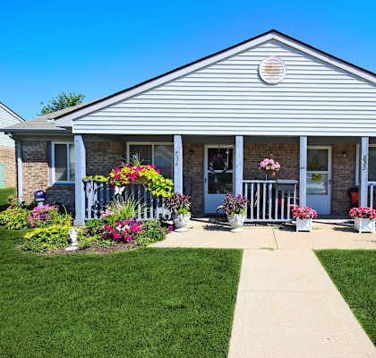 the front of a house with flowers on the porch