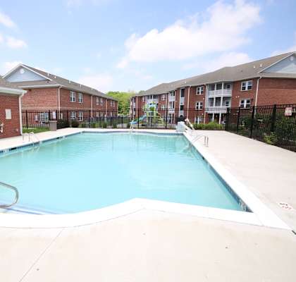 A swimming pool in a residential area with a blue sky and clouds.