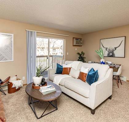 A living room with a white couch, a brown leather chair, and a coffee table. at Lake Shore Park, Ankeny, IA