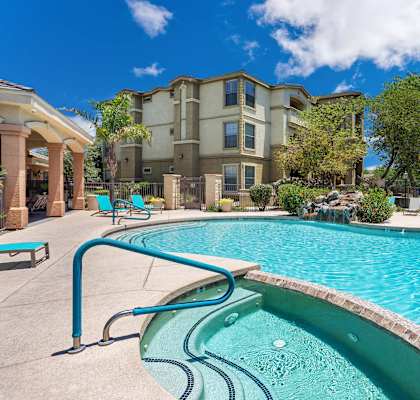 A swimming pool in front of a building with a blue sky in the background. at Superstition Canyon Apartments, Arizona