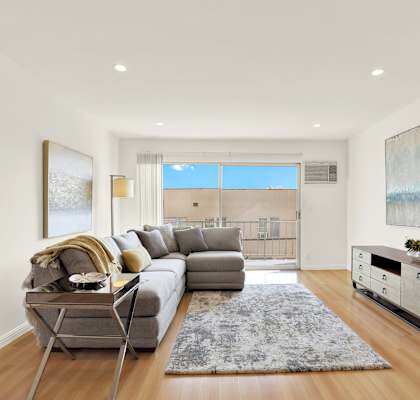 A modern living room with a grey sofa and a wooden floor at Wooster Encore Apartments, CA 90035