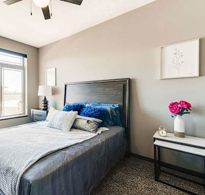 A modern bedroom with an oversized window, a bed on a wooden frame, and two nightstands.