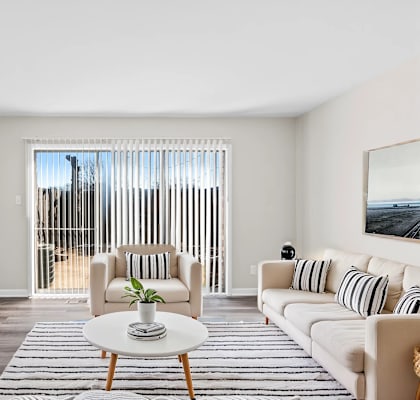 A living room with a white couch, a coffee table, and a television.