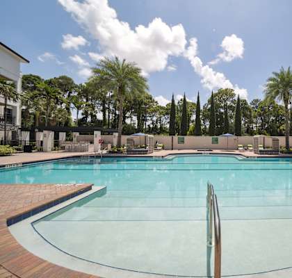 a large swimming pool with palm trees and apartments in the background