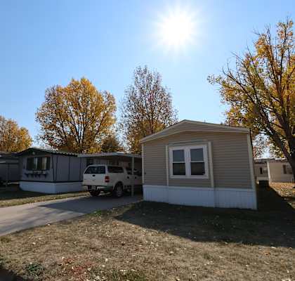 a row of mobile homes on a street with the sun shining over them at Mobile Home Village, Cheyenne, Wyoming