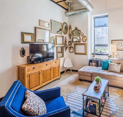 A living room with a blue chair and a wooden cabinet.