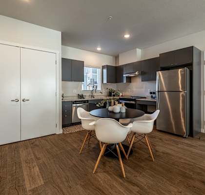 a kitchen with stainless steel appliances and a table and chairs at Sagecrest Apartments, Washington, 98801