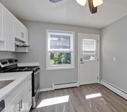 an empty kitchen with white cabinets and a white door and window at Laurel Ridge in Northampton, MA, 01060