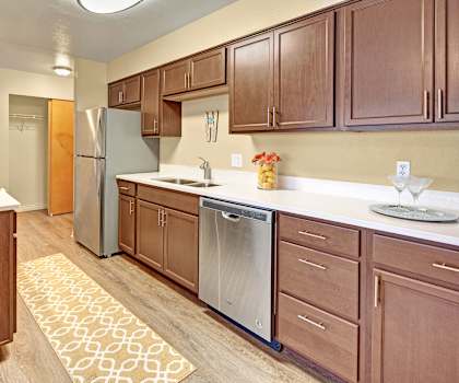 A kitchen with white countertops, brown cabinets, and dishware at Century Plaza. 