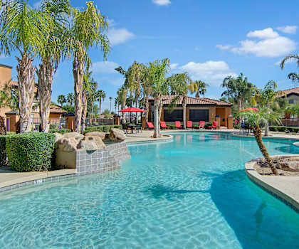 An outdoor pool surrounded by lounge chairs and palm trees at Arezzo. 