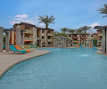 Resort style pool with palm trees and pool chairs around the pool at Aspire Pinnacle Peak. 