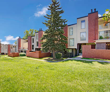The exterior of 3600 Brentwood showing salmon and cream walls, windows, balconies, and green space with grass and trees. 