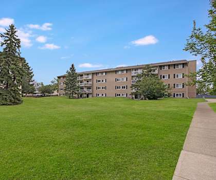 The outdoor area with a lawn and view of buildings at Cambridge West Apartments. 