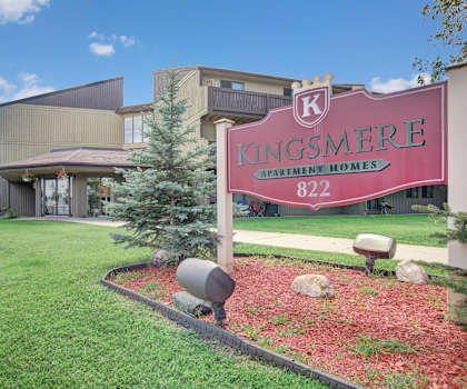 the sign for kingsmere apartment homes is in front of a lawn and a building