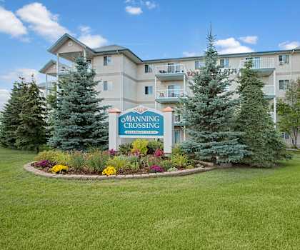 The exterior sign and building with trees and greenery of Manning Crossing Apartment Homes. 