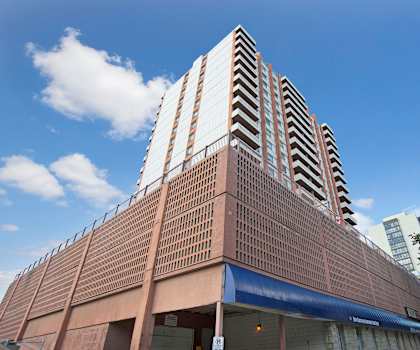 The exterior of brown and gray Marquis Towers building at viewed from the parking lot. 