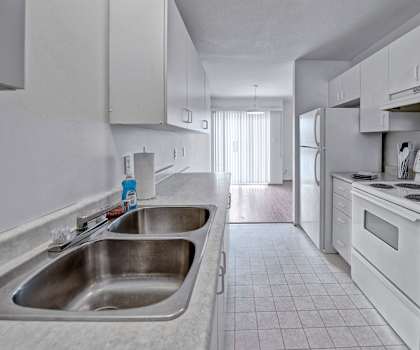A spacious, entirely white and gray kitchen with white appliances, light counter, and large wooden cabinets at Willow View Apartment Homes. 