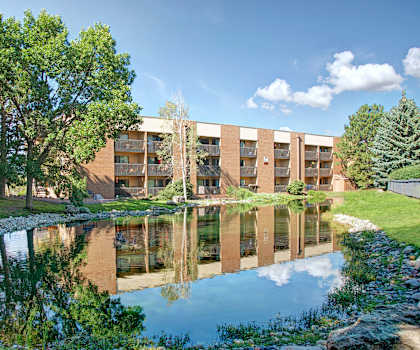 The exterior and green space with a pond at Eagle Ridge Apartments. 