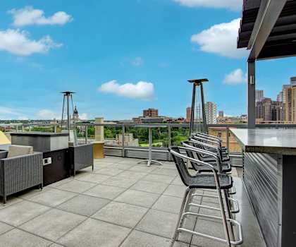 The rooftop balcony lounge with heaters, couches, chairs, coffee tables, and potted plants at Vue Apartment Homes. 