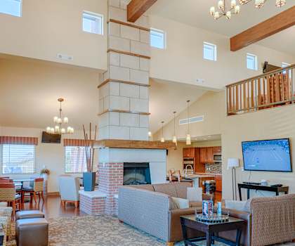 The resident lounge with a fireplace, couches, plush chairs, and coffee tables at Dakota Ridge Apartments. 