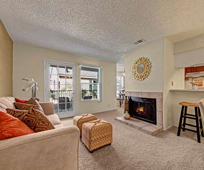 The living room with a couch, coffee table, decorations, a TV, and balcony at Cypess Pointe Apartments. 