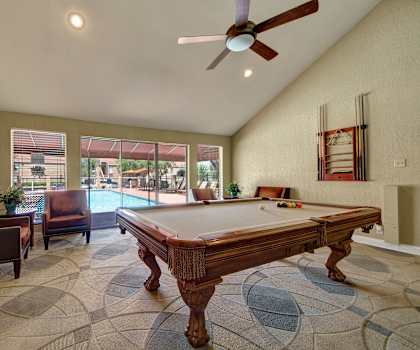 A wonderful resident lounge with plush, brown chairs, and a pool table at Trinity Place Apartment Homes. 