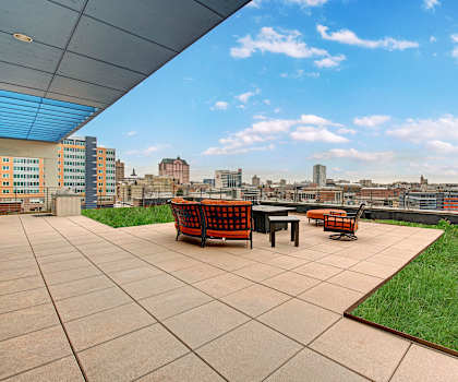 Rooftop lounge overlooking Milwaukee with chairs, tables, and some grass at Avenir. 